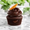 A dark chocolate and seville orange cacoa marmalade cups with candied orange rind on top on a marble counter